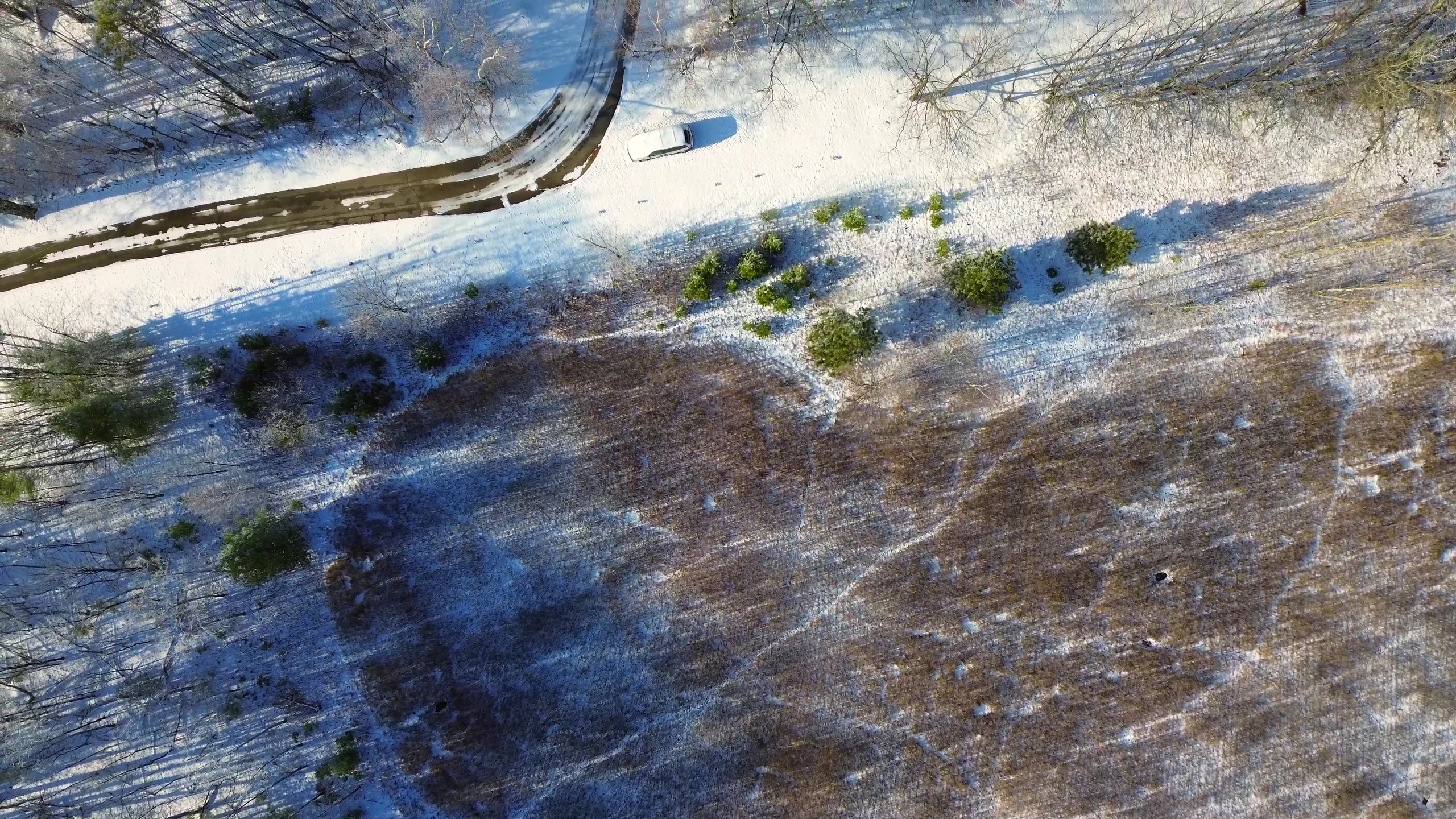 Overhead view of wooded acreage with a road and winter landscape